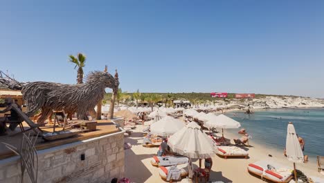 Club-De-Playa-Con-Bandera-Azul-En-Izmir-Cesme-Alacati,-Sombrillas-De-Playa,-Sillas,-Fiesta-En-La-Playa