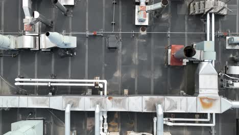 Large-rectangular-cube-ventilation-ducts-on-top-of-rooftop,-aerial-top-down-pan