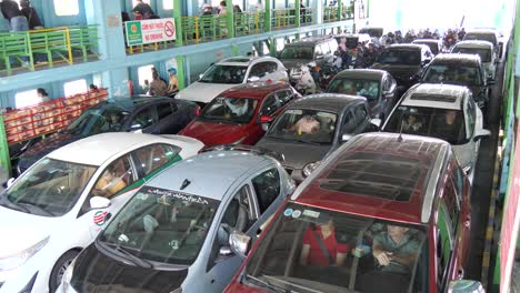 Cars-and-motorbikes-crowded-on-a-ferry,-people-inside-waiting-for-departure