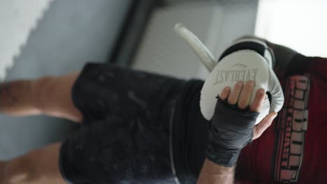 Vertical---male-fighter-put-boxing-glove-on-hand-before-sparring,-Czechia