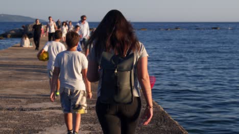 People-walking-on-a-pier-at-Kalamata-port,-Peloponnese,Greece-during-golden-hour,-medium-shot