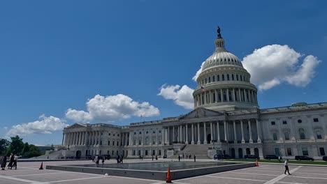 Slow-motion,-4K-panning-shot-of-the-United-States-Capitol-exterior,-capturing-its-iconic-dome,-architectural-details,-an-array-of-black-cars,-and-clouds