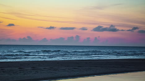 Farbenfroher-Sonnenuntergang-über-Einem-Ruhigen-Strand-Mit-Sanften-Wellen-Und-Einem-Heiteren-Himmel,-Zeitraffer