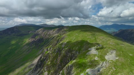 Cloud-shadows-moving-up-rounded-ancient-mountain-with-flight-towards-distant-peaks-under-overcast-sky