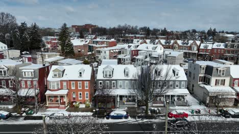 Aerial-approaching-shot-of-snowy-row-of-houses-and-car-on-street