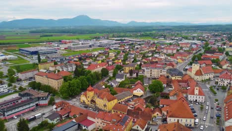 Drone-moves-push-in,-cityscape-of-Slovenska-Bistrica,-Slovenia,-highlighting-its-buildings-and-nearby-scenery