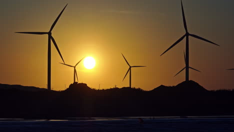 Long-lens-drone-shot-of-silhouettes-of-windturbines-and-kitesurfers-during-sunset-in-Brazil