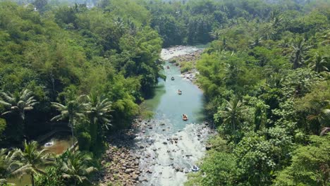 Drohnenansicht-Von-Menschen,-Die-Auf-Dem-Fluss-Raften,-Umgeben-Von-Grüner-Baumvegetation