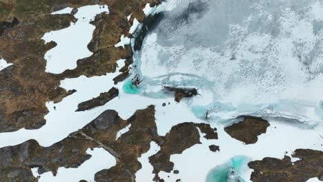 Tundra-Congelada-Con-Piscinas-De-Agua-De-Deshielo-De-Un-Azul-Vibrante-En-Medio-De-Nieve-Y-Terreno-Rocoso-En-Noruega