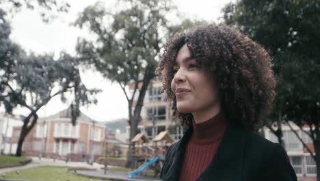 Una-Mujer-Con-Traje-Y-Pelo-Rizado-Camina-Mirando-Alrededor-En-La-Ciudad-De-Bogotá,-Colombia.