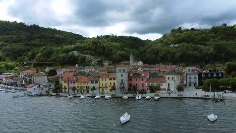 Colorful-buildings-and-boats-on-the-shore-of-Lake-Orta,-Piedmont,-Italy-aerial