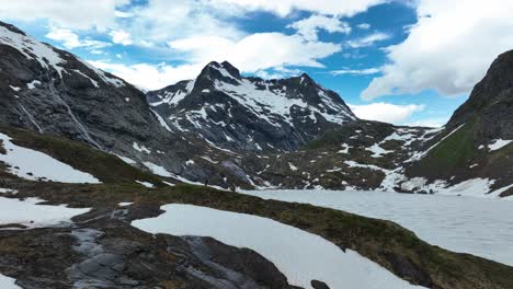 Couple-hiking-in-Norway's-Blavatnet,-scenic-snowy-mountains-and-bright-blue-sky