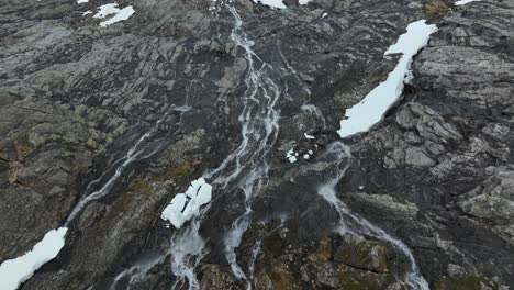 Rocky-landscape-with-streams-and-patches-of-snow-in-norway,-aerial-view