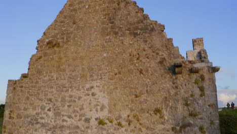 Terryland-Castle-on-River-Corrib,-Galway-Ireland,-drone-tilts-down-along-brick-wall-ruins