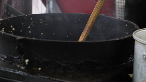 Cooking-And-Stirring-Kettlecorn-In-Cauldron-Using-Wooden-Spoon