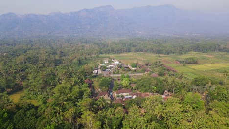 Reveal-drone-shot-of-"Balkondes-Wanurejo"-and-Junkyard-Park-with-Menoreh-Hill-on-the-background