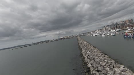 Cinematic-FPV-drone-fly-over-video-of-the-jetty-and-marina-on-the-south-coast-of-england-during-a-hot-and-cloudy-summers-day-by-the-coast-of-england