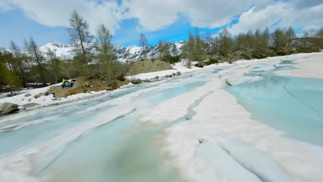 Drone-flying-at-low-altitude-over-Lagazzuolo-iced-lake-during-winter-season,-Valmalenco-in-Italy