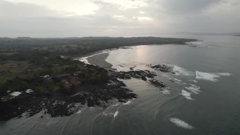 Santa-catalina-coastline-in-panama-at-dusk-with-waves-crashing-on-the-rocky-shore,-aerial-view