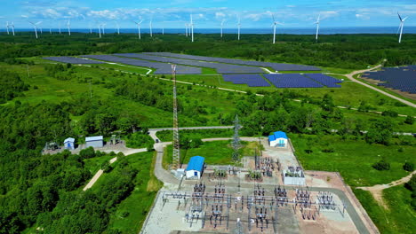 Aerial-drone-rotating-shot-over-a-solar-power-plant-and-windmills-in-the-background-in-an-offshore-wind-farm-in-Paldiski,-Estonia-at-daytime