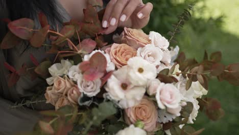 Nahaufnahme-Eines-Straußes-Mit-Rosen-Und-Grünpflanzen,-Gehalten-Von-Einer-Frau-Mit-Manikürten-Nägeln