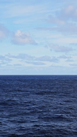 Océano-Abierto-Y-Fondo-Marino-Con-Horizonte-Y-Cielo-Azul,-Suaves-Olas-Y-Oleaje-En-Una-Vasta-Extensión-De-Agua-Infinita,-Video-Vertical-Para-Redes-Sociales,-Carretes-De-Instagram-Y-Tiktok