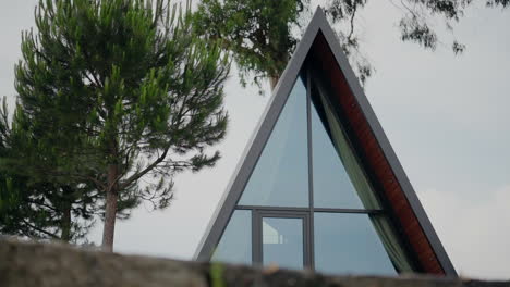 Modern-A-frame-house-with-large-glass-windows-surrounded-by-lush-greenery-and-trees