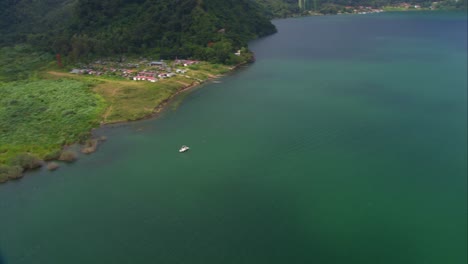 Impresionante-Toma-Aérea-Desde-Un-Helicóptero-Captura-La-Serena-Belleza-Del-Lago-De-Atitlán,-Rodeado-De-Exuberante-Vegetación-Y-Montañas-Volcánicas.