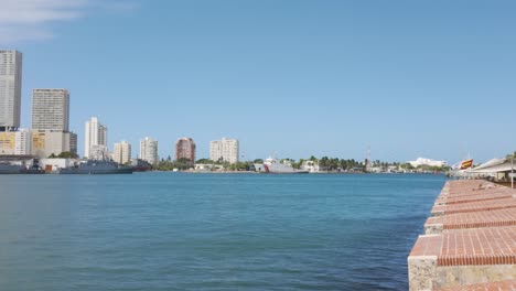 Vista-Panorámica-Del-Paseo-Marítimo-De-Cartagena-Con-Cielo-Azul-Y-Aguas-Tranquilas,-Mostrando-El-Horizonte-De-La-Ciudad.