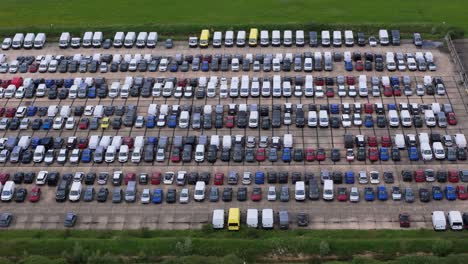 Thousands-of-unwanted-new-and-used-motors-aerial-view-across-stored-on-RAF-Thurleigh-airfield-runway,-Bedfordshire,-England