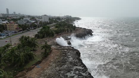 Aerial-forward-view-of-ocean-waves-crash-against-the-rocky-coastline-of-Santo-Domingo-after-Hurrican-Beryl,-Dominican-Republic