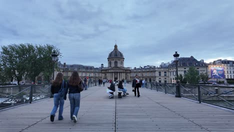 Fußgänger-Auf-Der-Pont-Des-Arts-Mit-Dem-Institut-De-France-Im-Hintergrund-In-Paris