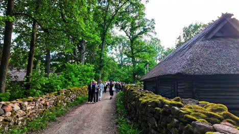 Zeitlupenlandschaft-Mit-Menschen,-Die-Auf-Einem-Wanderweg-Neben-Einem-Holzhaus-Im-Parkdorf-Spazieren-Gehen,-Dem-Estnischen-Freilichtmuseum-In-Tallinn,-Europa,-Reisetourismus