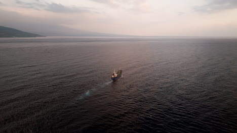 Big-cargo-ship-navigating-the-open-seas-off-Bali-North-Coast,-aerial-arc