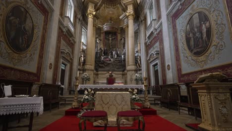 Kunstvolles-Inneres-Des-Heiligtums-Bom-Jesus-Do-Monte-In-Braga,-Portugal,-Mit-Einem-Kunstvoll-Verzierten-Altar-Mit-Einem-Kruzifix,-Umgeben-Von-Detaillierten-Religiösen-Gemälden-Und-Säulen