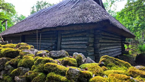 Passing-a-wooden-small-house-on-the-side-of-a-sand-path-behind-a-stone-wall-in-Tallinn,-Estonia-in-slowmotion