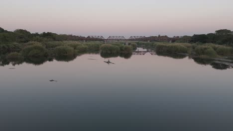 Low-level-push-forward-towards-an-old-railway-bridge-crossing-Komati-River,-South-Africa,-aerial-shot