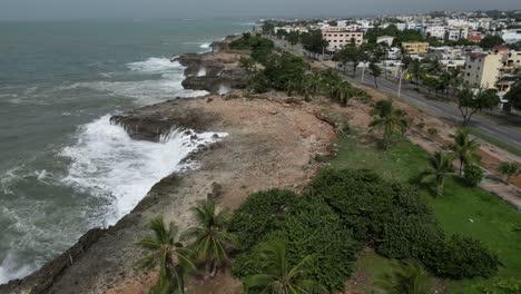 -Aerial-backward-view,-waves-crash-against-rocky-coastline-after-Hurricane-Beryl