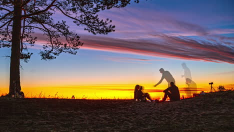 Fast-motion-fusion-time-lapse-montage-of-people-sitting-gathering-outdoors-with-afternoon-sky-sunset-horizon-on-beach-by-tree-landscape-travel-holidays