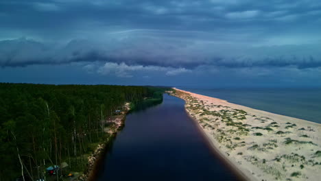 Scenic-aerial-view-of-a-serene-river-flowing-between-a-lush-forest-and-a-sandy-beach-at-dusk