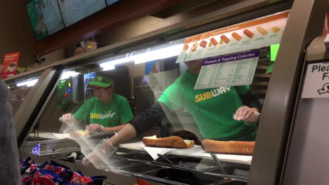 Die-Bewegung-Eines-Arbeiters,-Der-In-Einem-Subway-Restaurant-Mit-4K-Auflösung-Ein-Sandwich-Für-Den-Kunden-Zubereitet