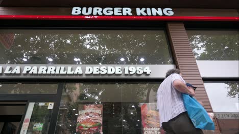 Vista-De-ángulo-Bajo-De-Peatones-Pasando-Por-La-Cadena-Americana-De-Restaurantes-De-Comida-Rápida-De-Hamburguesas,-Burger-King