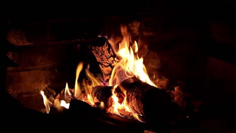 Warm-wood-crackling-fireplace-with-glowing-flames-in-slow-motion---tranquil-outdoor-dark-evening