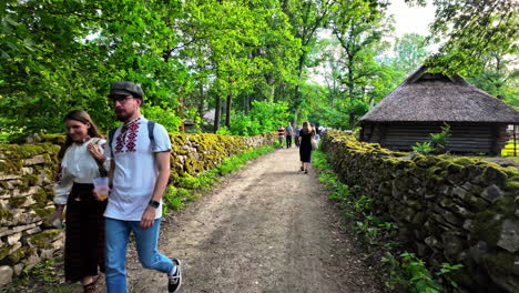 Spaziergang-Auf-Einem-Sandweg-Durch-Einen-Grünen-Wald,-Links-Und-Rechts-Steinmauern,-Zeitlupe,-Kleines-Haus-Rechts