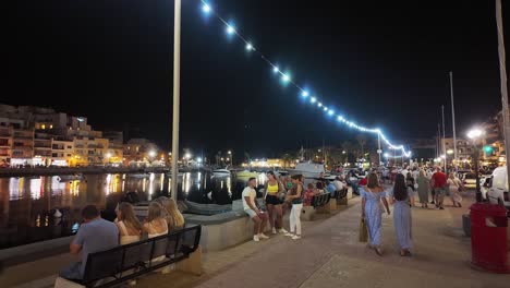 Young-and-old-people-sit-on-benches-and-walk-on-the-promenade-in-the-center-of-Marsaskala-along-the-bay-on-a-summer-evening-in-Malta