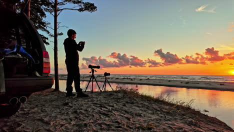 Hombre-Tomando-Fotografías-Del-Amanecer-Al-Atardecer-En-La-Playa,-Cámara-Filmando-El-Cielo