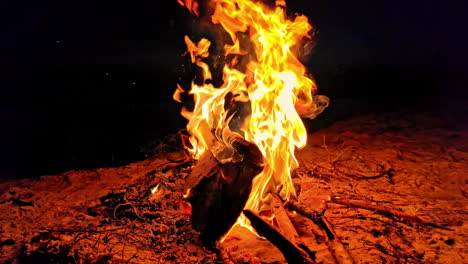 Fire-burning-on-a-beach-in-darkness,-big-flames-in-slowmotion