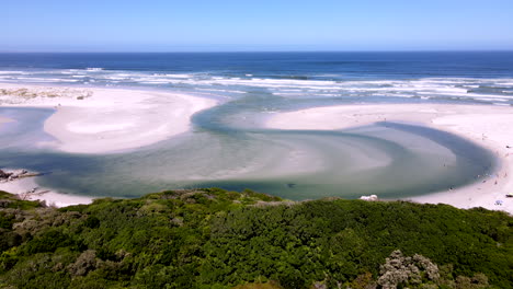 Drone-tilt-up-reveal-scenic-Klein-River-lagoon-estuary-river-mouth-breaching-into-ocean-over-famous-Grotto-Beach-in-Hermanus-on-the-Overstrand