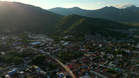 Aerial-View-Establishing-Shot-Roldanillo-Town-Park-at-Sunset-with-Three-Crosses-Hill-at-Distance