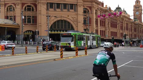 Melbourne's-bustling-central-business-district,-with-trams-running-along-the-street,-vehicles-traffic,-pedestrians-crossing,-and-commuters-rushing-to-Flinders-Street-Railway-Station